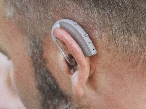 Ein modernes Hörgerät sitzt hinter dem Ohr eines Mannes für bessere Hörakustik.