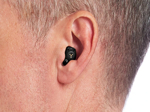 Mann mit modernen, schwarzen Hörgerät im Ohr zur diskreten Hörverstärkung.