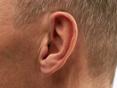 Ein Mann mit Hörgerät am Ohr, Nahaufnahme für Hörakustik und Hörgeräteversorgung.