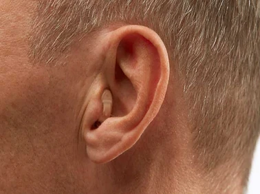 Mann mit Hörgerät im Ohr, Nahaufnahme zur Veranschaulichung moderner Hörhilfen.